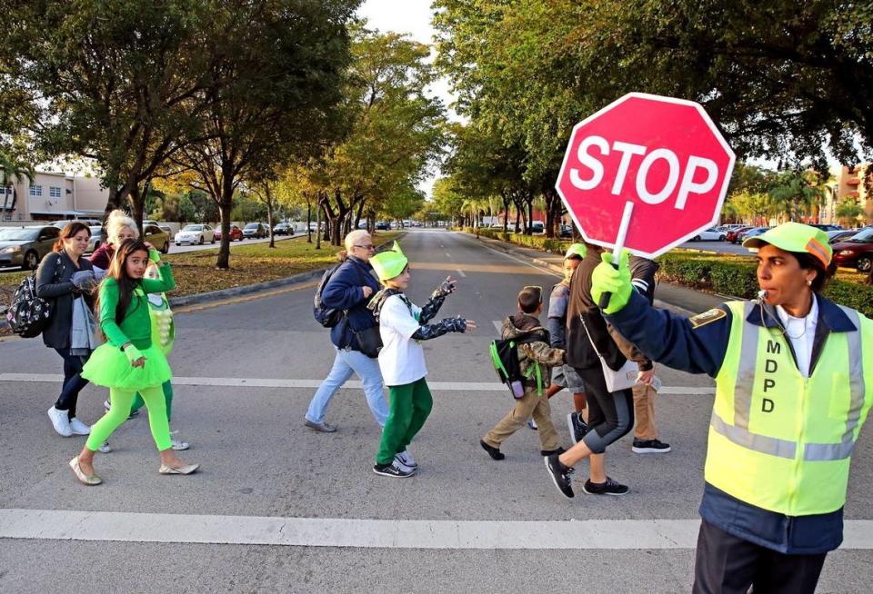 A Miami-Dade crossing guard stops traffic as Wesley Matthews Elementary students cross Southwest 122nd Avenue in a Tamiami neighborhood in this 2017 file photo.