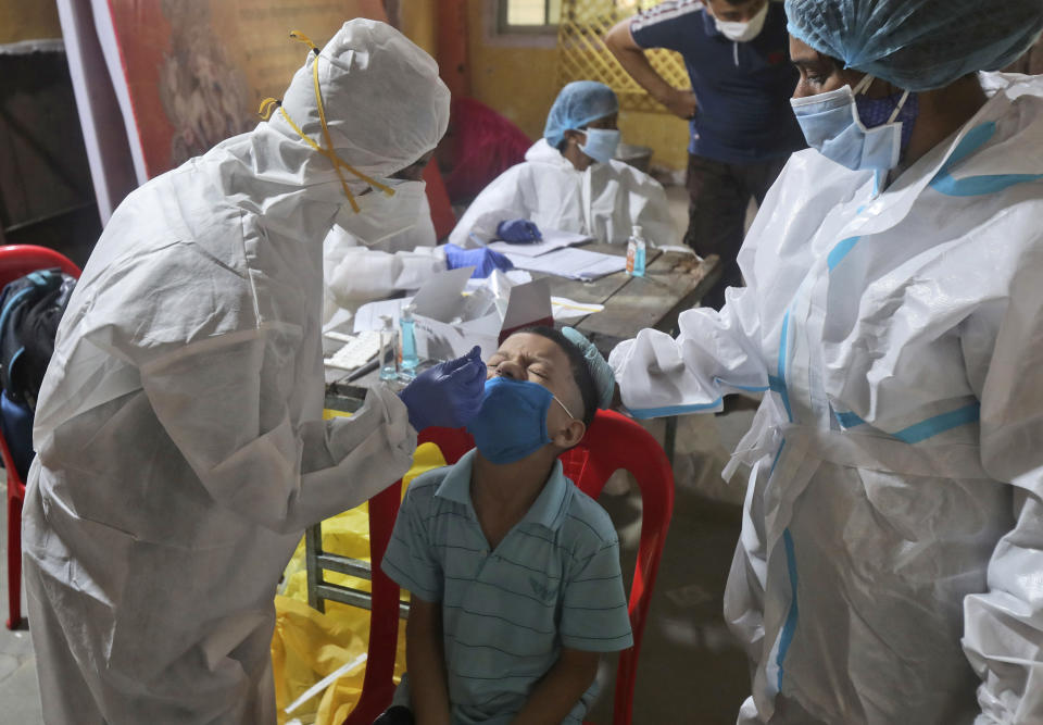 Health workers collect a swab sample to test for COVID-19 in Mumbai, India, Wednesday, Sept. 16, 2020. India's total of coronavirus infections passed 5 million Wednesday, still soaring and testing the feeble health care system in tens of thousands of impoverished towns and villages. (AP Photo/Rafiq Maqbool)