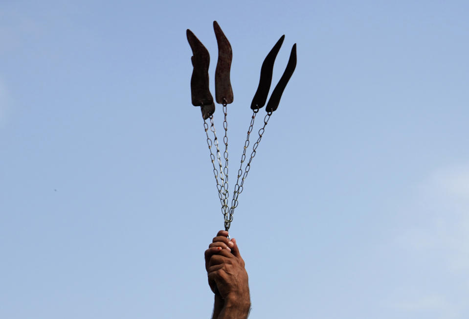 A Shiite Muslim flagellates himself with knifes on chains during a procession to mark Ashoura, in Islamabad, Pakistan, Friday, July 28, 2023. Ashoura is the Shiite Muslim commemoration marking the death of Hussein, the grandson of the Prophet Muhammad, at the Battle of Karbala in present-day Iraq in the 7th century. (AP Photo/Rahmat Gul)