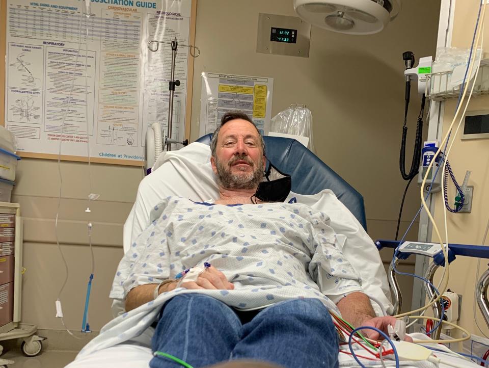Melissa Persling's ex-boyfriend Jim in the emergency room wearing a gown and hooked up to machines while on vacation looking at the camera