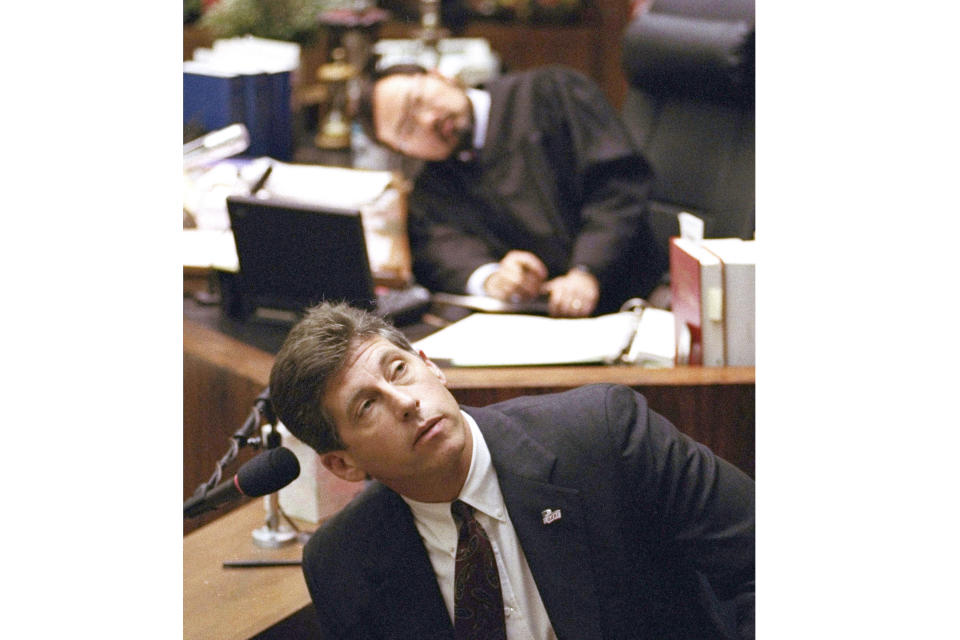 FILE - Los Angeles Police Department Det. Mark Fuhrman, foreground, and Superior Court Judge Lance Ito, rear, crane their heads to look at an overhead monitor during the O.J. Simpson double-murder trial, Friday, March 10, 1995, in Los Angeles. Fuhrman, 72, who was convicted of lying on the witness stand in the O.J. Simpson trial three decades ago, is now barred from law enforcement under a California police reform law meant to strip the badges of police officers who act criminally or with bias. (AP Photo/Reed Saxon, File)