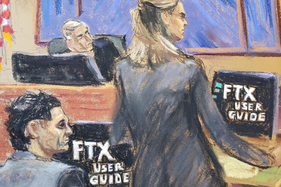 A courtroom sketch from United States v. Samuel Bankman-Fried shows a government prosecutor directing Sam Bankman-Fried and the judge to look toward screens displaying an “FTX user guide” video.