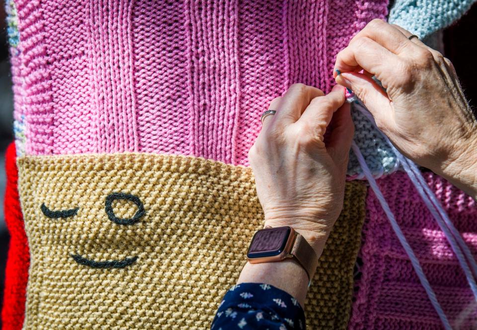 Mary Lostutter knits a sweater on a tree on the northeast corner of 6th Street and College Avenue for the Wrapped in Love event benefitting Bloomington's Middle Way House on Friday, September 24, 2021. Indiana Univeristy sophomore Macee Long was assisting Lostutter.