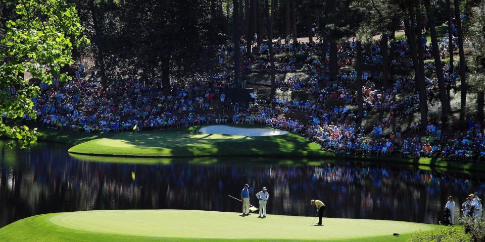 Crowds watch a golfer putt next to a water trap at Augusta National in 2019.