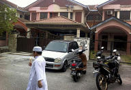 A Muslim boy leaves a mosque after Friday prayers, just down the road from the home of Fariq Abdul Hamid, co-pilot of the missing Malaysia Airlines jetliner MH370, center, Friday, March 14, 2014 in Shah Alam, Malaysia. The pilots of the missing Malaysia Airlines passenger jet were a contented middle-aged family man passionate enough about flying to build his own simulator and a 27-year-old contemplating marriage who had just graduated to the cockpit of the Boeing 777. Details about the men have emerged from interviews with neighbors, Malaysia Airlines staff, a religious leader and from social networks and news reports in Malaysia and Australia.(AP Photo/Eileen Ng)