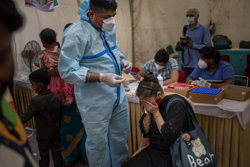 A woman reacts as a health worker waits to take her nasal swab sample to test for COVID-19 at a bus terminal in New Delhi, India, Wednesday, March 24, 2021. (AP Photo/Altaf Qadri)