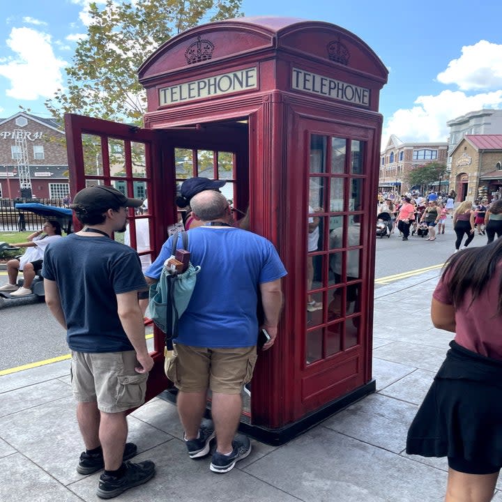 A photo of a telephone booth with guests inside of it