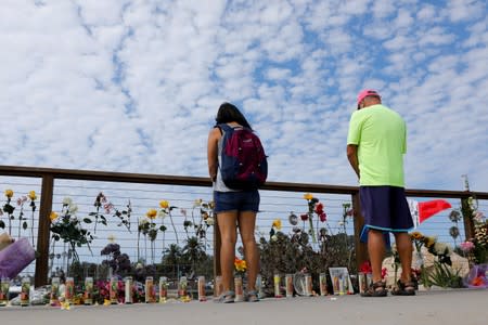 People strop to pause over a makeshift memorial near Truth Aquatics as the search continues for those missing in a pre-dawn fire that sank a commercial diving boat off a Southern California island near Santa Barbara, California