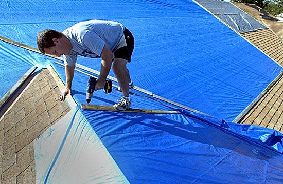 A man secures tarps to his house in Delray Beach after Hurricane Wilma in 2005. Following the disastrous hurricane seasons in 2004 and 2005, utilities have been required to boost resiliency and the ability to recover quicker from future storms. FPL said it had 3.2 million outages because of Wilma and it took an average of 5.4 days to restore power. But after 2017's Hurricane Irma knocked out power to 4.4 million, it took FPL an average of 2.1 days to restore power.