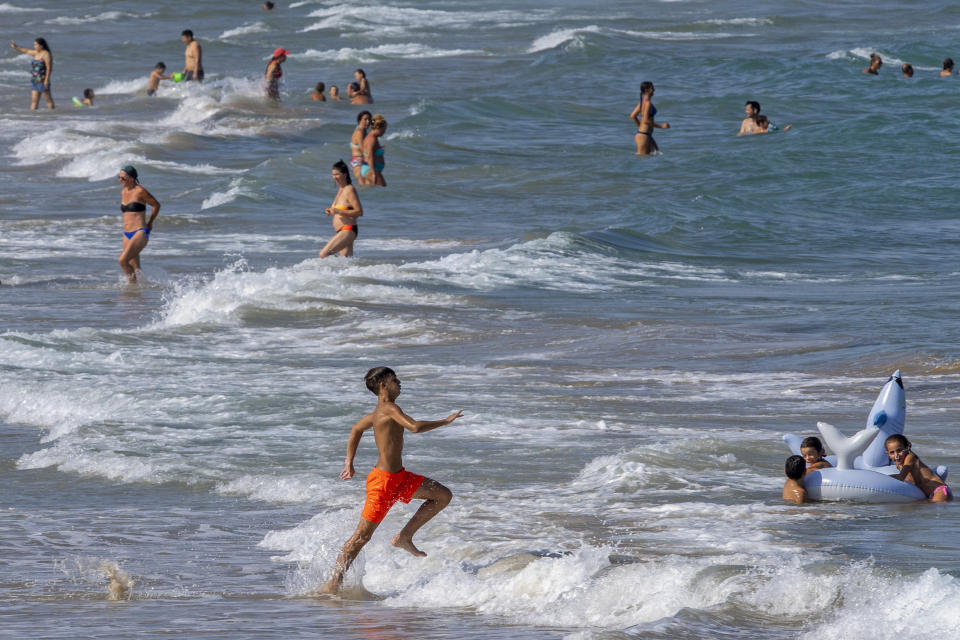 Gente refrescándose en la playa de Puerto de Sagunto, en el este de España, el martes 16 de agosto de 2022. Mientras los veraneantes disfrutan del calor estival en el Mar Mediterráneo, los científicos climáticos advierten de las sombrías consecuencias para su vida marina de un calentamiento impulsado por sucesivas olas de calor. (AP Foto/Alberto Saiz)