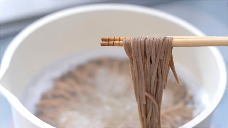 Boiling soba noodles with chopsticks 