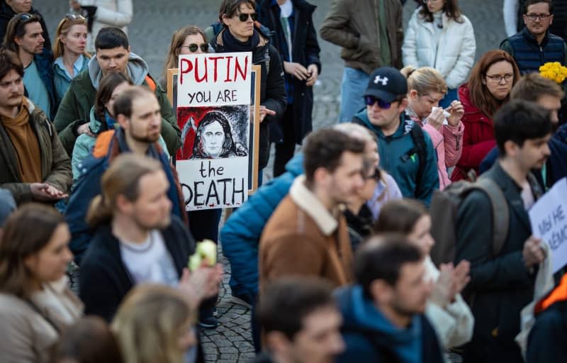 A participant holds a sign with the words Putin you are the death during a prayer service for leading Russian opposition figure Alexei Navalny, who died in prison while serving a 19-year sentence, at Schillerplatz in Stuttgart. Christoph Schmidt/dpa
