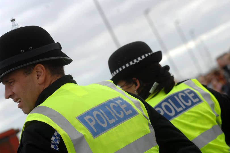 Image of the back of two police officers with a profile view of one of them.