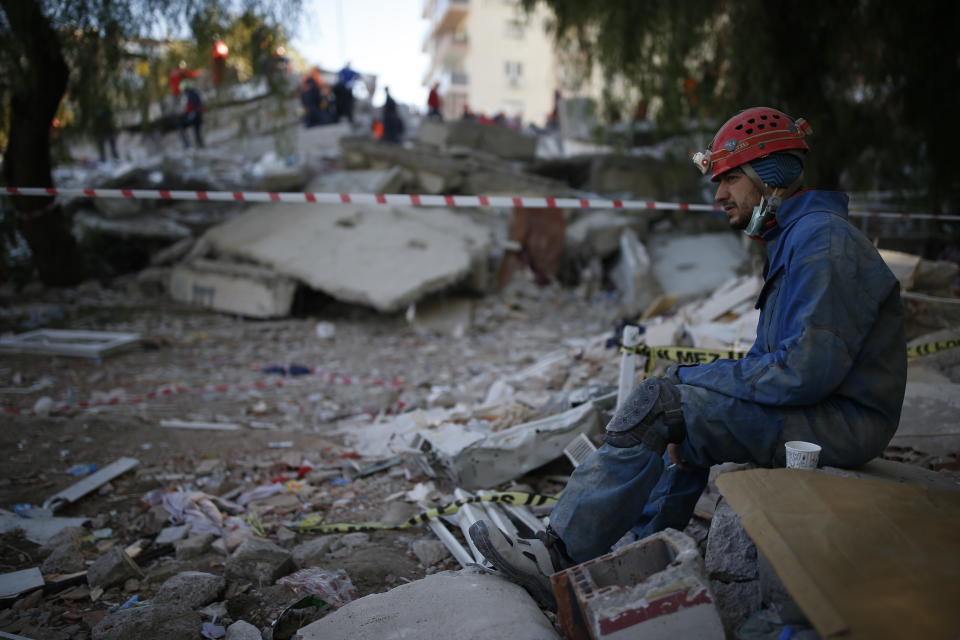 A member of rescue services rests during search operations in the debris of a collapsed building for survivors in Izmir, Turkey, Sunday, Nov. 1, 2020. Rescue teams continue ploughing through concrete blocs and debris of collapsed buildings in Turkey's third largest city in search of survivors of a powerful earthquake that struck Turkey's Aegean coast and north of the Greek island of Samos, Friday Oct. 30, killing dozens Hundreds of others were injured.(AP Photo/Emrah Gurel)