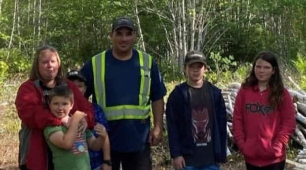 Elaine Heighton, left, stands with her husband, Quincy, and their four children on the lot in the village of Tatamagouche, N.S., about 50 kilometres north of Truro, where community members volunteered to build them a new house after they became homeless. (Friends of the Heightons/GoFundMe - image credit)