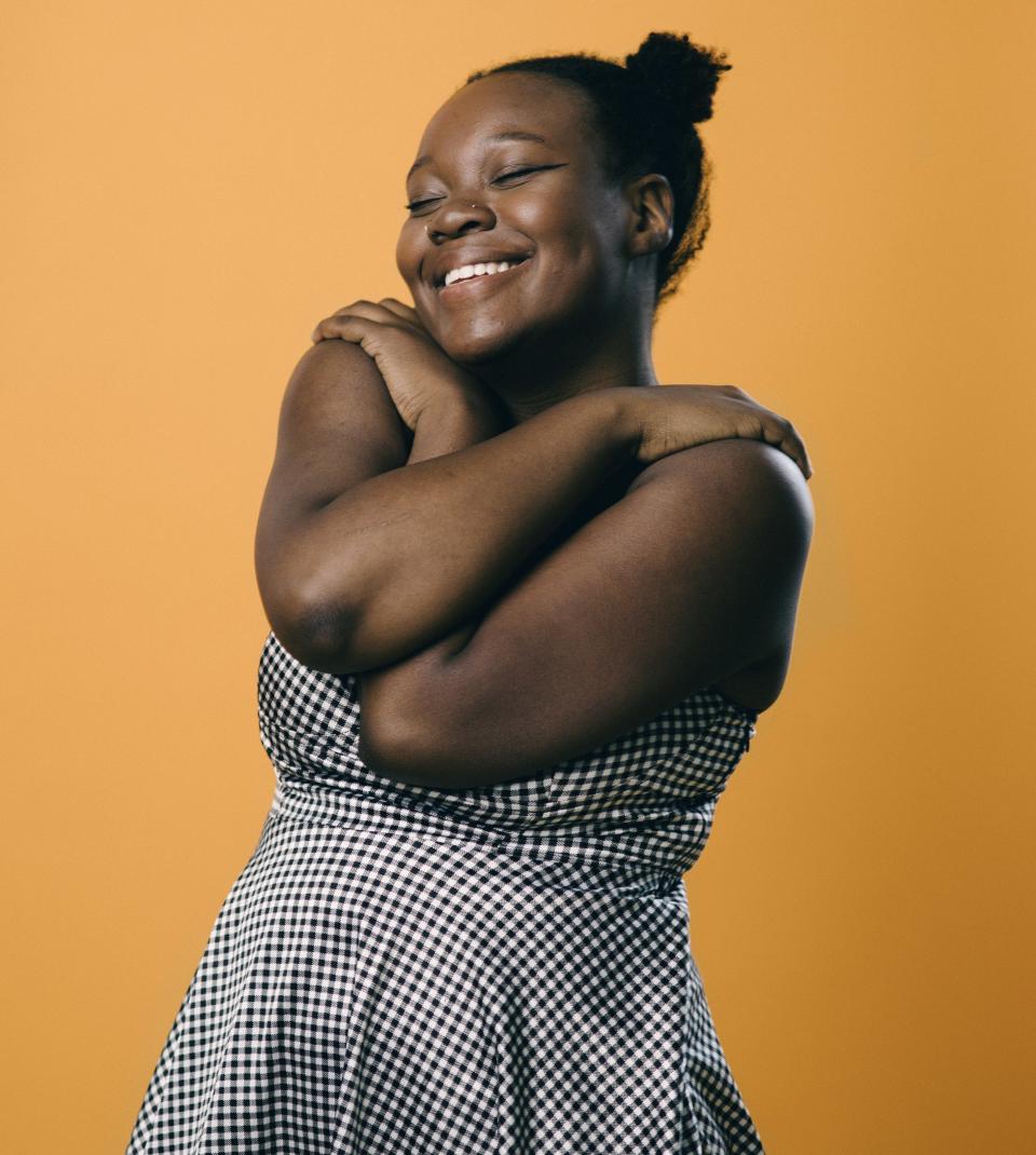 A woman smiles and wraps her arms around herself