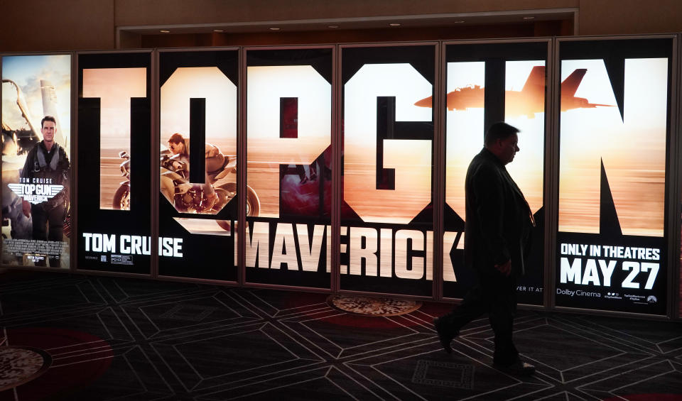 An attendee walks past an advertisement for the upcoming film "Top Gun: Maverick" on the opening day of CinemaCon 2022, the official convention of the National Association of Theatre Owners (NATO) at Caesars Palace, Monday, April 25, 2022, in Las Vegas. (AP Photo/Chris Pizzello)