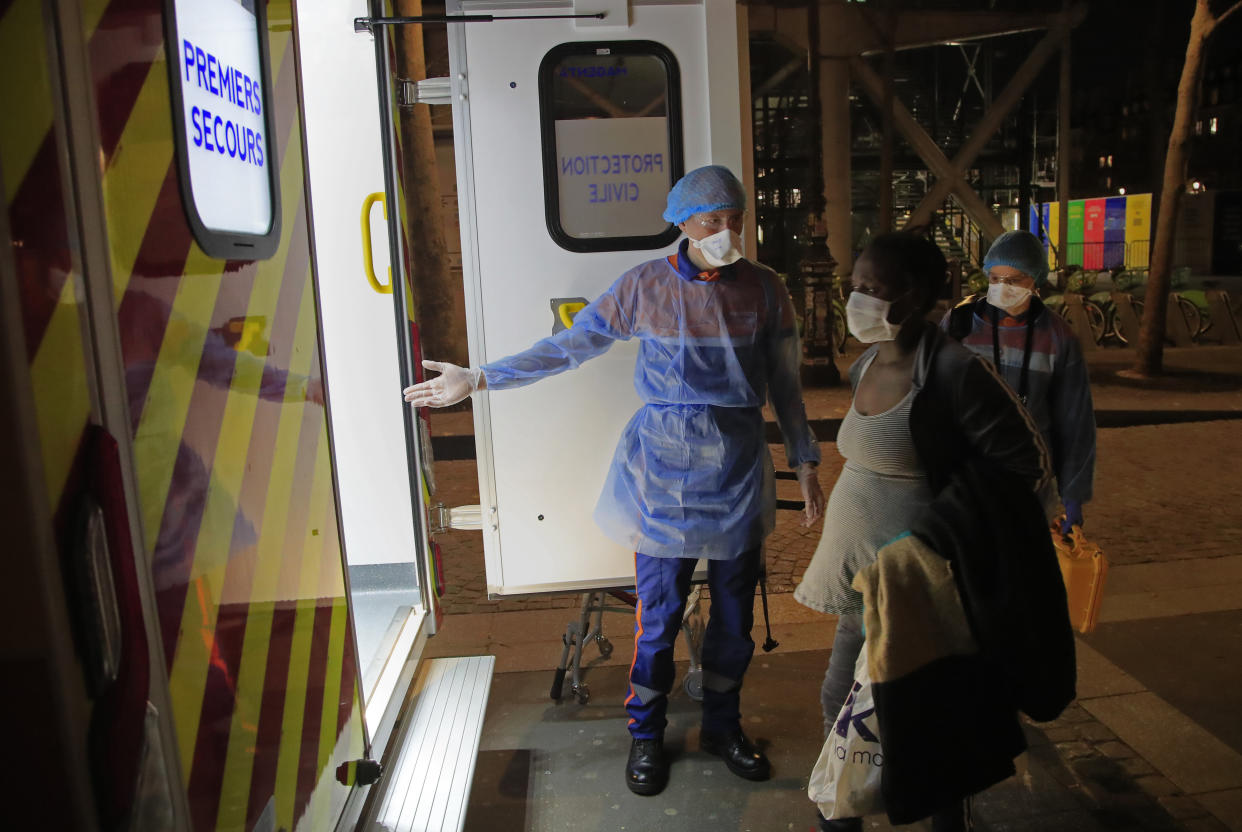 Members of the Protection Civile with protective mask Vincent Jactel, left, and Aurore Lejeune, right, escort a pregnant 27 year old woman suspected of having the coronavirus infection to an ambulance in Paris, Thursday, March 26, 2020. For most people, the new coronavirus causes only mild or moderate symptoms, such as fever and cough. For some, especially older adults and people with existing health problems, it can cause more severe illness, including pneumonia. (AP Photo/Michel Euler)