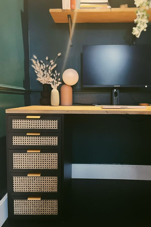 A dark green desk with rattan-fronted drawers