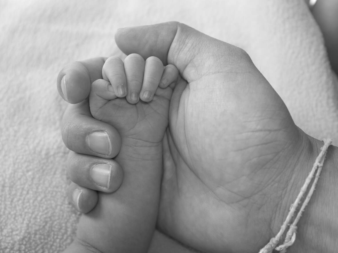 A mother holds a newborn baby's hand in a stock image. A lawsuit alleges a litany of abuses occurred at United Church of Canada-owned maternity homes across Canada, including one in Winnipeg. (GOLFX/Shutterstock - image credit)