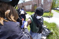 Registered nurse Lillye Neal administers a syringe of Moderna COVID-19 vaccine to Kenneth West in Detroit, Wednesday, May 12, 2021. In three weeks, more than 40 people have received vaccinations through the program to reach people who normally have little to no access to churches, community centers or other places where vaccines are being given. Mobile care teams consisting of two nurses and a peer support specialist accompany The Salvation Army's Bed & Bread trucks as they cruise Detroit, which lags far behind the state and nearby communities in percentage of people vaccinated. (AP Photo/Paul Sancya)