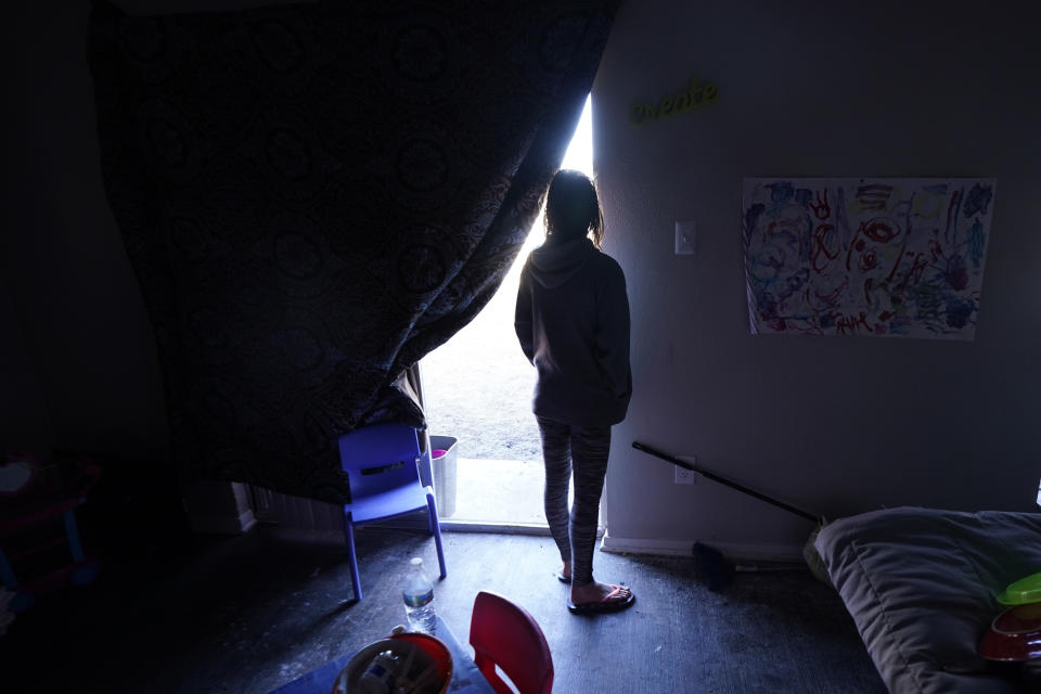 FILE - In this Feb. 23, 2021, file photo, Ricki Mills looks out from her home as she waits for a fire hydrant to be turned to get water, in Dallas. The single mother had her apartment flooded last week by a pipe that burst during the record winter cold and was waiting for repairs to restore water to the apartment complex. On Thursday, Feb. 25, 2021 managers of Texas' power grid are expected to receive a lashing in the first public hearings about the crisis at the state Capitol. (AP Photo/LM Otero File)