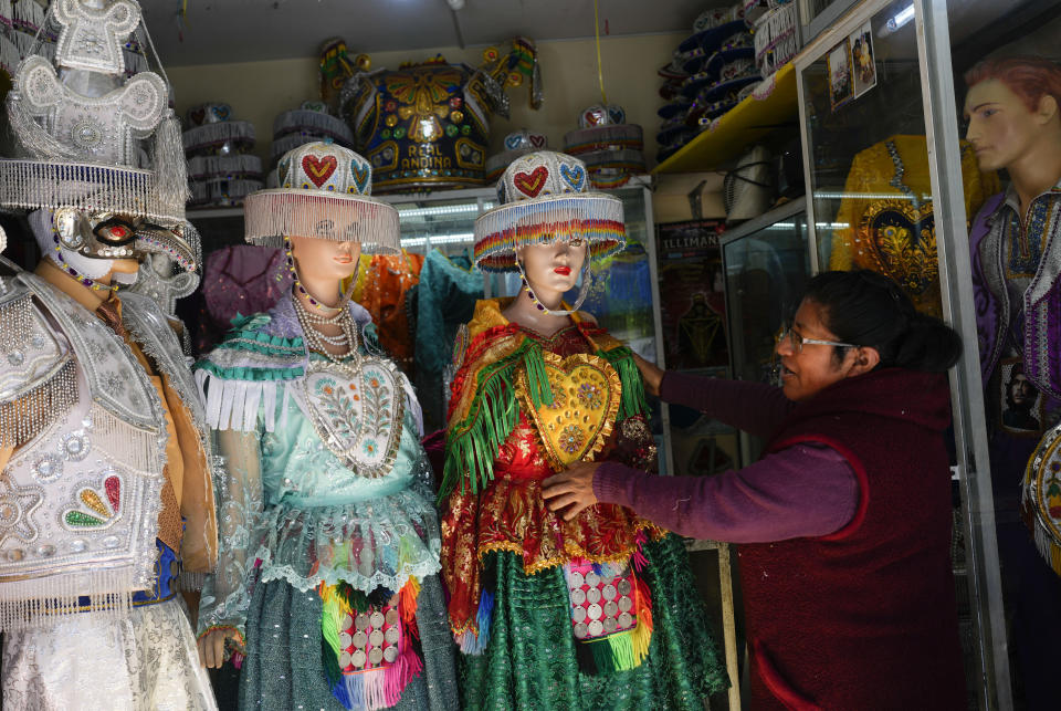 Una costurera ajusta uno de sus vestidos usados por las mujeres que realizan el baile "La Llamerada" en la próxima Fiesta anual del Señor Jesús del Gran Poder, mientras espera que los bailarines los recojan en una tienda en La Paz, Bolivia, el miércoles 22 de mayo de 2024. La celebración de una semana de duración muestra el folclore andino y comienza el 23 de mayo. (Foto AP/Juan Karita)