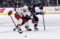 Winnipeg Jets' Mark Scheifele (55) and Carolina Hurricanes' Brendan Smith (7) skate after the loose puck during the second period of an NHL game in Winnipeg, Manitoba, Tuesday, Dec. 7, 2021. (Fred Greenslade/The Canadian Press via AP)