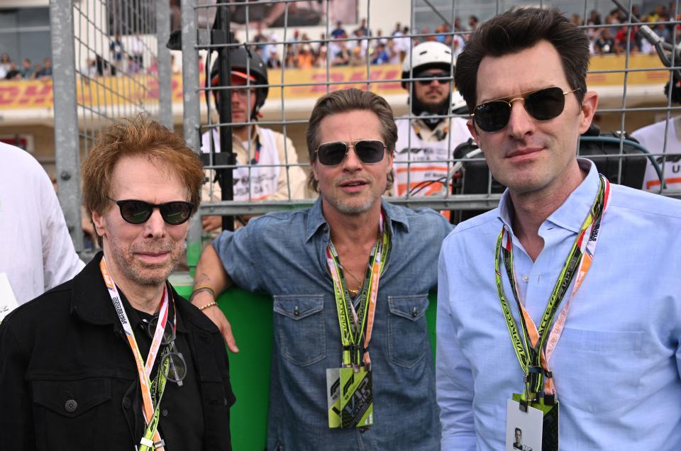 Producer Jerry Bruckheimer, Brad Pitt and director Joseph Kosinski await the start of the Formula One United States Grand Prix. (Photo by Patrick T. FALLON / AFP) (Photo by PATRICK T. FALLON/AFP via Getty Images)