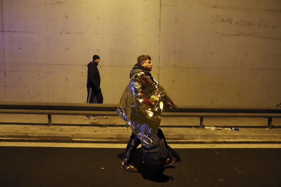 A passenger walks on a road after a train collision in Larissa city, Greece, early Wednesday, March 1, 2023. The collision between a freight train and and oncoming passenger train occurred early Wednesday and resulted in the derailment of several train cars, police said. (AP Photo/Vaggelis Kousioras)