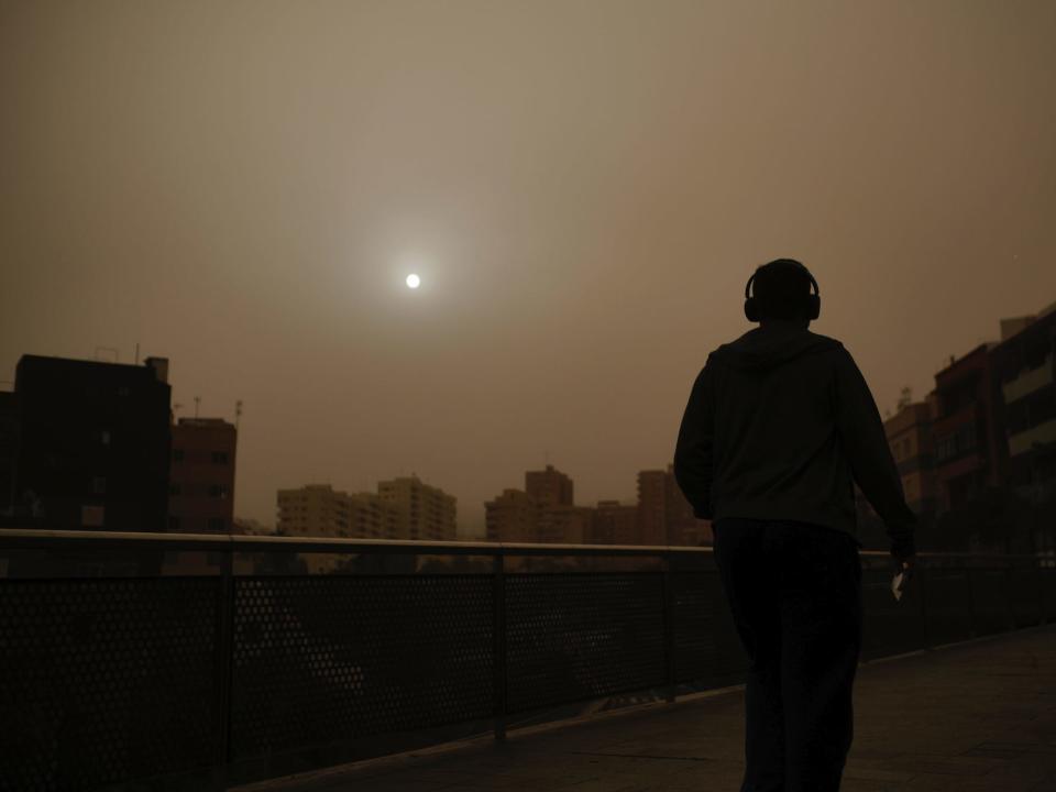 A man walks beneath a cloud of red dust in Santa Cruz de Tenerife, Spain, on February 22.