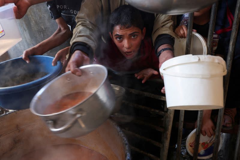 FILE PHOTO: Palestinians gather to get their share of charity food offered by volunteers, amid food shortages, in Rafah