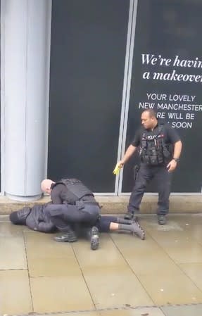 A police officer points a taser while the other holds a man down outside Arndale shopping center, where several people have been stabbed, in Manchester