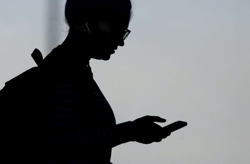 FILE - In this Nov. 14, 2019, file photo, a woman checks her phone in Orem, Utah, USA. Britain's Information Commissioner's Office on Wednesday Jan. 22, 2020, released a new set of standards aimed at protecting children's online personal details privacy for social media sites, games and other online services. (AP Photo/Rick Bowmer, File)