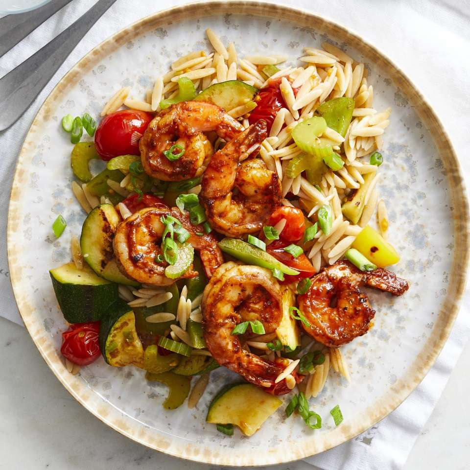 <p>In this healthy BBQ shrimp recipe, shrimp are seasoned with a peppery spice blend and served with zucchini, peppers and whole-grain orzo for a delicious and easy dinner that's ready in just 30 minutes. The shrimp and veggies are cooked in the same skillet, so cleanup is a snap too.</p> <p> <a href="https://www.eatingwell.com/recipe/273726/peppery-barbecue-glazed-shrimp-with-vegetables-orzo/" rel="nofollow noopener" target="_blank" data-ylk="slk:View Recipe" class="link ">View Recipe</a></p>