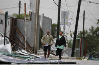 Tourists walk past debris littering the street after Hurricane Zeta's landfall in Playa del Carmen, Mexico, early Tuesday, Oct. 27, 2020. Zeta is leaving Mexico’s Yucatan Peninsula on a path that could hit New Orleans Wednesday night. (AP Photo/Tomas Stargardter)