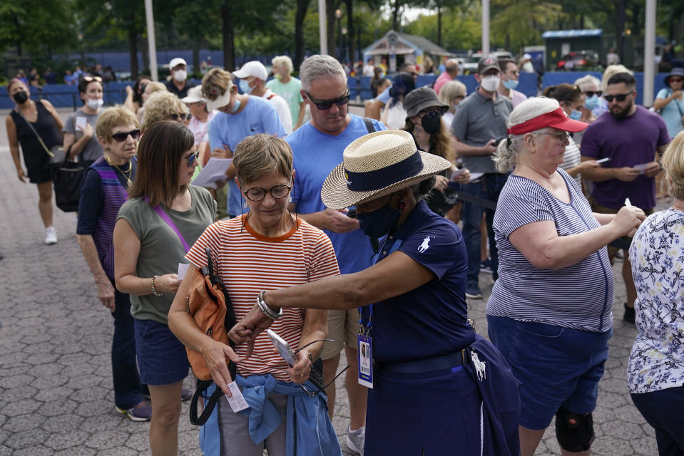 Tennis fans show their proof of vaccination cards for entry to attend the first round of the US Open tennis championships, Monday, Aug. 30, 2021, in New York. (AP Photo/Seth Wenig)