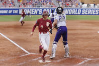 Florida State's Devyn Flaherty (9) scores next to Washington catcher Sydney Stewart during the second inning of an NCAA softball Women's College World Series game Saturday, June 3, 2023, in Oklahoma City. (AP Photo/Nate Billings)