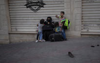 A Palestinian family sit on the street side after they were evacuated from a building following Israeli airstrikes on Gaza City, Wednesday, May 12, 2021. Rockets streamed out of Gaza and Israel pounded the territory with airstrikes early Wednesday as the most severe outbreak of violence since the 2014 war took on many of the hallmarks of that devastating 50-day conflict, with no endgame in sight. (AP Photo/Khalil Hamra)