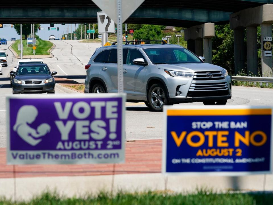 Signs in favor and against a Kansas Constitutional amendment on abortion are displayed next to a street.