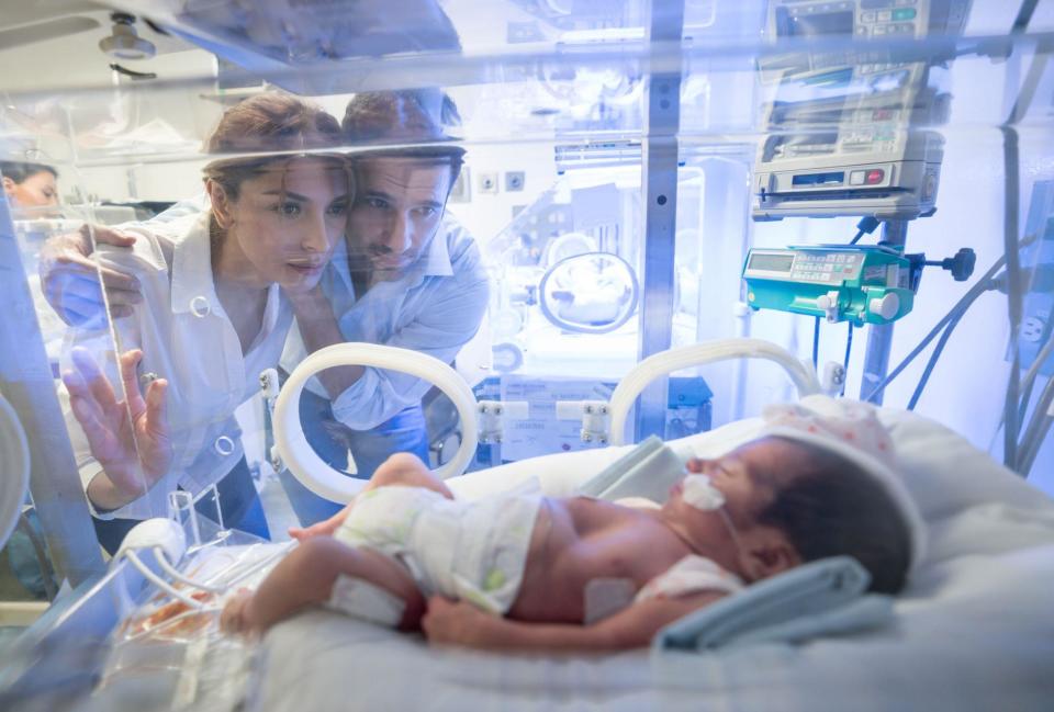 Padres miran a un bebé en una incubadora