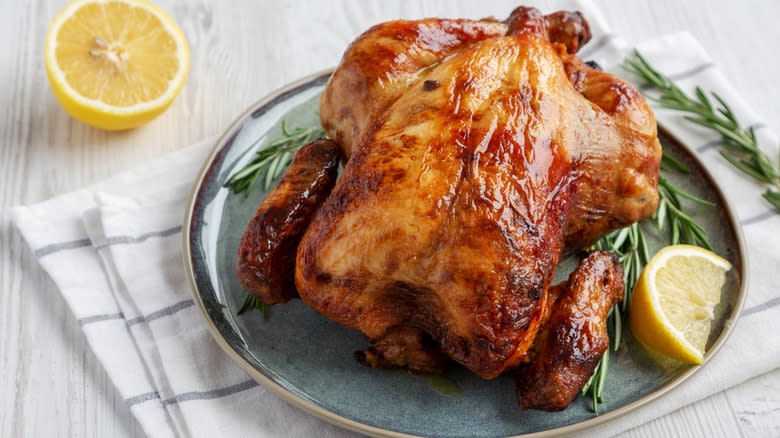 Rotisserie chicken on a plate with lemon and rosemary