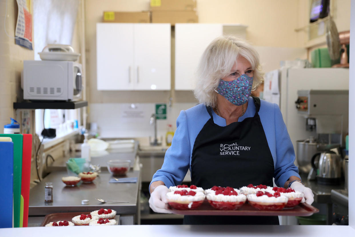 Britain's Camilla, Duchess of Cornwall, in her role as President, Royal Voluntary Service, serves up a trifle dessert as she works in the kitchen during a visit to the Royal Voluntary Service Mill End lunch club in Rickmansworth, Hertfordshire on October 8, 2020, to meet volunteers who have overcome recent challenges posed by the novel coronavirus COVID-19 pandemic to reinstate the much-needed lunch sessions. (Photo by Andrew Matthews / POOL / AFP) (Photo by ANDREW MATTHEWS/POOL/AFP via Getty Images)