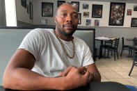 Travis Riddle sits at a table inside his restaurant, Country Boy Cooking, in Brunswick, Ga., on Oct. 5, 2021. Riddle was among hundreds in the community who took part in marches and rallies demanding justice after Ahmaud Arbery was chased and killed on Feb. 23, 2020. Three white men charged in the slaying of Arbery are scheduled to stand trial, with jury selection in the case set to start Monday, Oct. 18. (AP Photo/Russ Bynum)