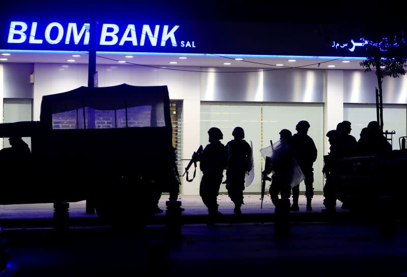 Lebanese army soldiers are silhouetted as they stand guard outside a branch of Blom Bank during a protest against growing economic hardship in Sidon