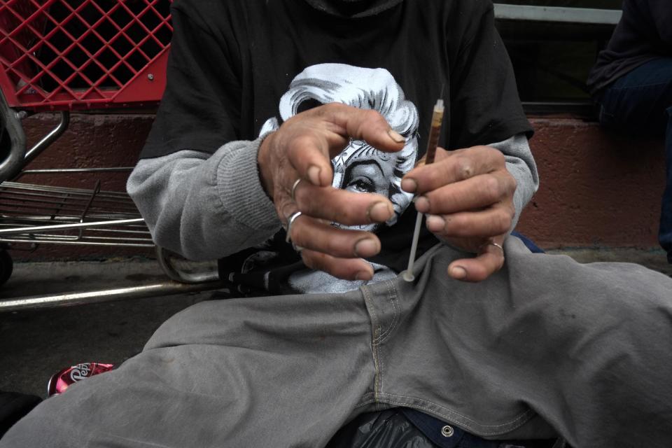 FILE - In this Monday, May 6, 2013 file photo, a drug addict prepares a needle to inject himself with heroin in front of a church in the Skid Row area of Los Angeles. It's not a rare scene on Skid Row to spot addicts using drugs in the open, even when police patrol the area. Jim Hall, an epidemiologist who studies substance abuse at Nova Southeastern University in Fort Lauderdale, Fla. says, the striking thing about heroin’s most recent incarnation in the early 21st Century, is that a drug that was once largely confined to major cities is spreading into suburban and rural towns across America, where it is used predominantly by young adults between the ages of 18 and 29. "We haven’t really seen something this rapid since probably the spread of cocaine and crack in the mid-1980s," Hall said. (AP Photo/Jae C. Hong)