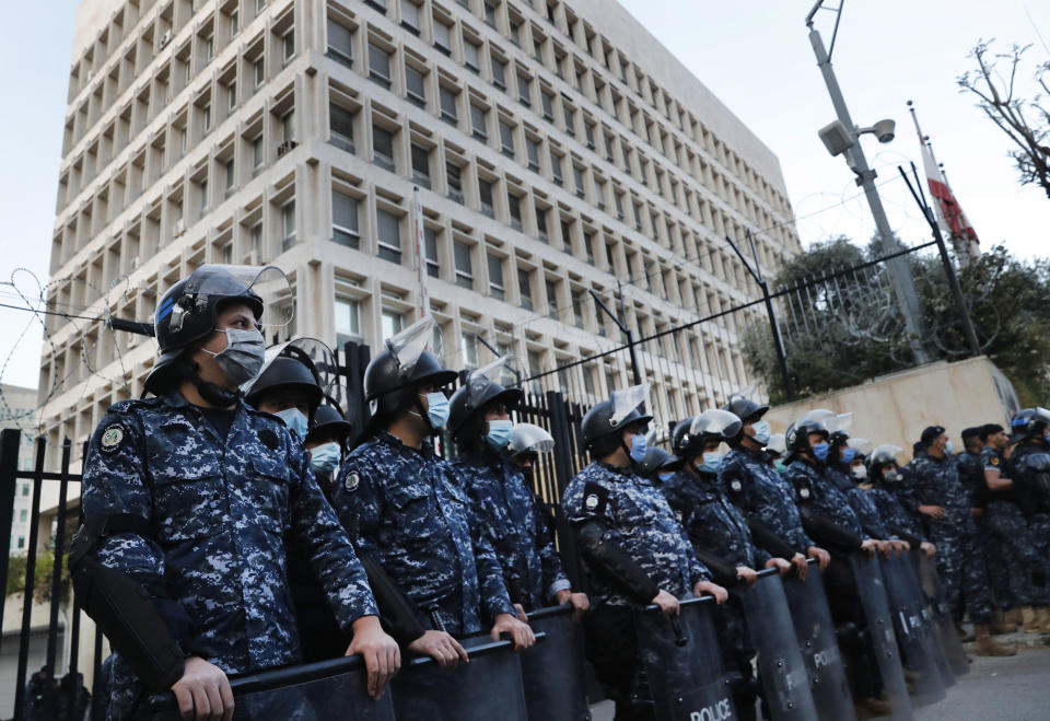 FILE - In this April 23, 2020 file photo, Lebanese riot police stand guard in front the central bank building, where the anti-government protesters protest against the Lebanese central bank's governor Riad Salameh and the deepening financial crisis, in Beirut, Lebanon. An economic meltdown, a revolution, financial collapse, a virus outbreak and a cataclysmic explosion that virtually wiped out the country's main port. The past year has been nothing short of an earthquake for tiny Lebanon, with an economic meltdown, mass protests, financial collapse, a virus outbreak and a cataclysmic explosion that virtually wiped out the country’s main port. Yet Lebanese fear even darker days are ahead. (AP Photo/Hussein Malla, File)