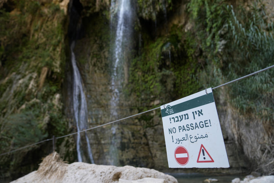 A warning sign at a waterfall near the site of a rockslide that took place in the Ein Gedi Nature Reserve, on the western shore of the Dead Sea, a popular tourist site in Israel, Thursday, Aug. 24, 2023. An avalanche of rock tumbled down a hillside near the Dead Sea, Israeli medics said, injuring several people, including children. (AP Photo/Ohad Zwigenberg)