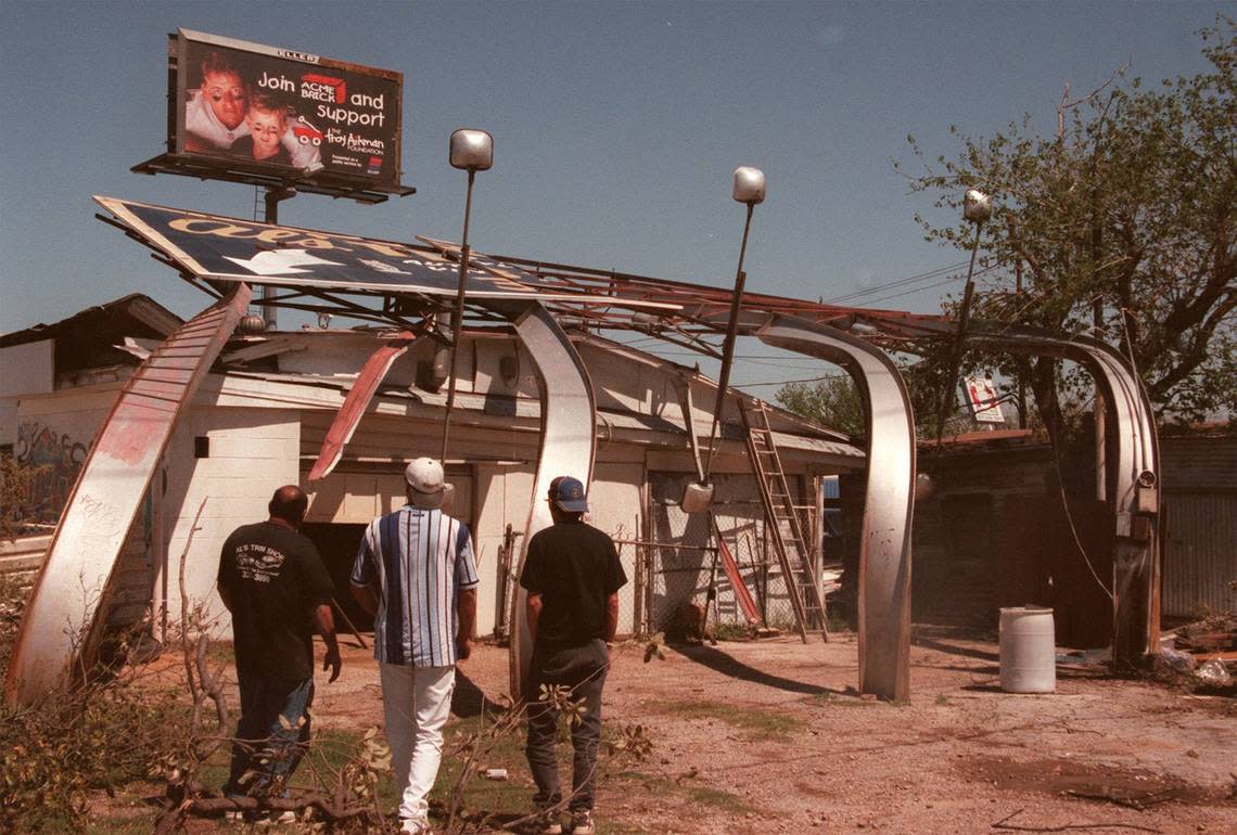 Neighbors and employees of Al’s Trim shop, near University and 7th streets, marvel at the damage caused by a tornado the day before on March 28, 2000.