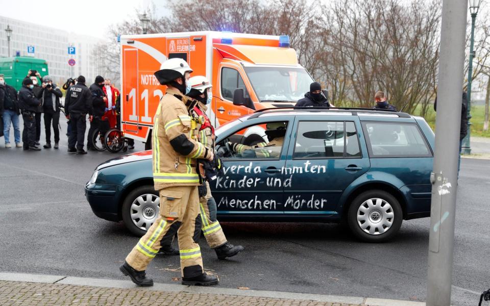 Firefighters remove the car that crashed into the gate - FABRIZIO BENSCH /REUTERS